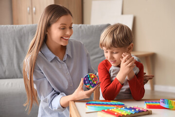 Female psychologist with pop it fidget toy and little boy in office. World Autism Awareness Day