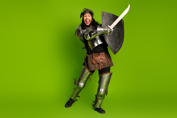 Medieval knight character in armor holding a sword and shield on a vibrant green background...