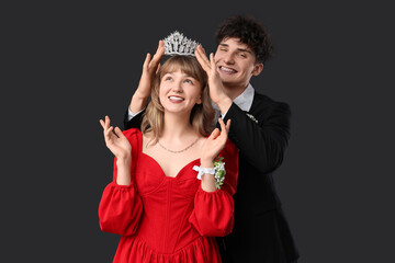 Young boy crowning his prom date on black background