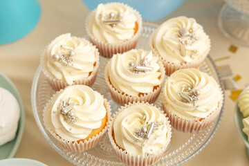 Dessert stand with tasty white cupcakes for birthday party on table
