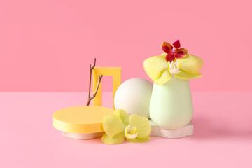 Decorative podiums with beautiful orchid flowers and tree branch on pink background
