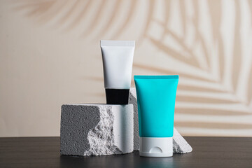Plastic white tube for cream or lotion. Skin care or sunscreen cosmetic with stylish props and palm...