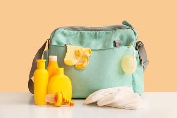 Baby bag with fruit nibbler on table against beige background