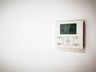 Modern digital thermostat mounted on a clean white wall interior