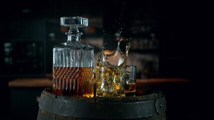 Detail of pouring ice cube into whiskey. Freeze motion drink preparation.