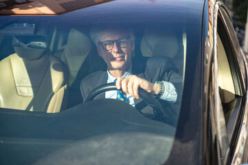 A professional businessman drives his electric car to work, navigating morning traffic with focus...