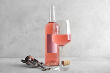 Obraz premium Glass, bottle of pink wine and corkscrew with cork on table against white background