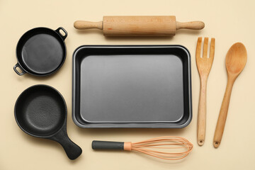 Baking tray with kitchen utensils on beige background. Top view