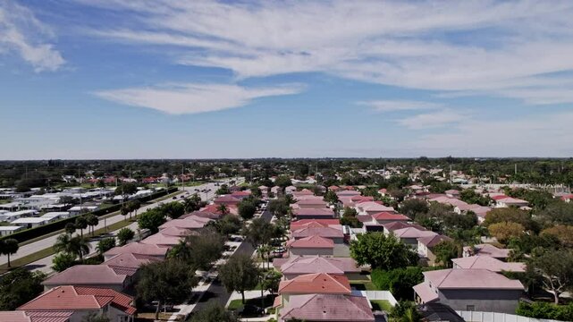 Aerial: West Palm Beach residential zone during the day with blue sky, establishing drone shot, USA