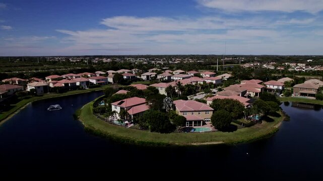 Aerial: West Palm Beach residential zone during the day with lagoon, parallax drone shot, USA