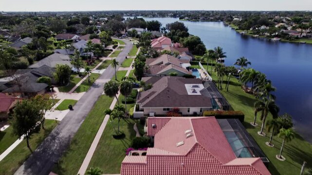 Aerial: West Palm Beach residential zone during the day with lagoon, push in tilt up drone shot, USA