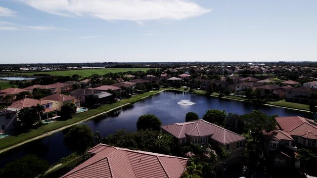Aerial: West Palm Beach residential zone during the day with small lake, dolly in drone shot, USA