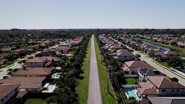 Aerial: West Palm Beach residential zone during the day with a road in the middle, establishing drone shot, symmetric, USA