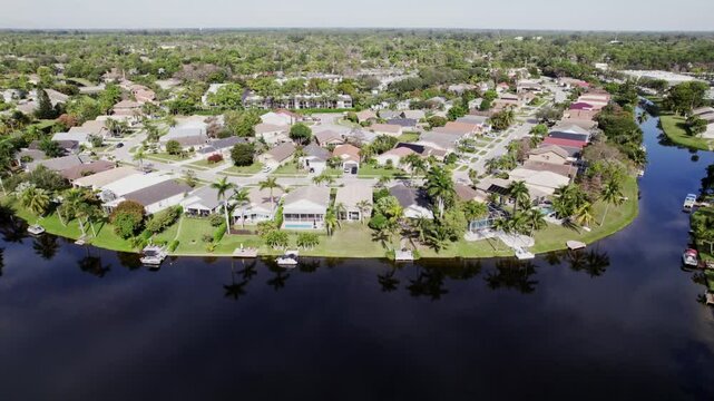 Aerial: West Palm Beach residential zone during the day with lagoon, orbit drone shot, USA
