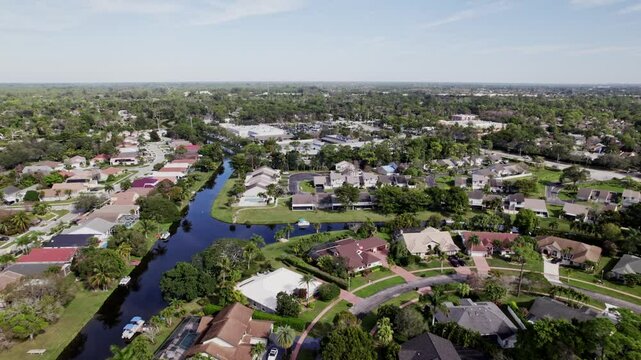 Aerial: West Palm Beach residential zone during the day with lagoon, push in drone shot, USA