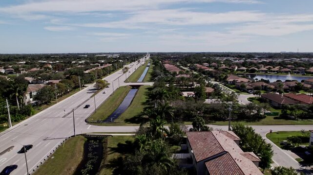 Aerial: West Palm Beach residential zone during the day with a road, establishing drone shot, USA