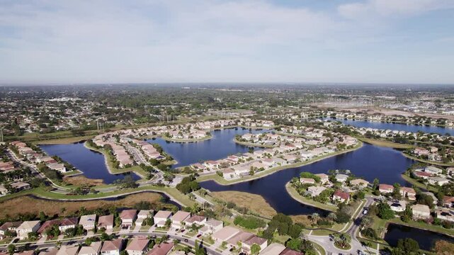 Aerial: West Palm Beach residential zone during the day with bodies of water, orbit drone shot, USA