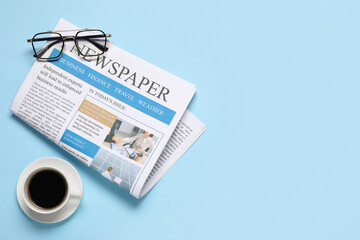 Newspaper, eyeglasses and cup of coffee on blue background. Top view