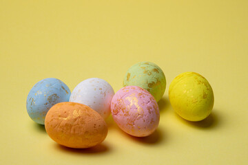 Decorated easter eggs in pastel colors arranged on a plain yellow background