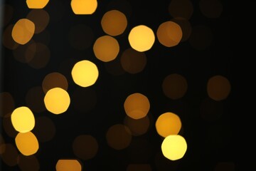 Blurred view of golden lights on black background. Bokeh effect