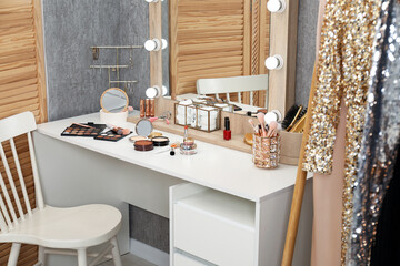 Makeup room. Mirror, dressing table, different beauty products and chair indoors