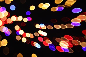 Blurred view of colorful lights on black background, bokeh effect