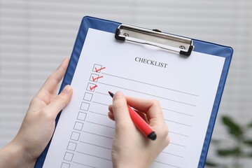 Woman filling Checklist on blurred background, closeup