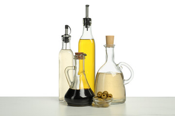 Salad dressings and olives on table against white background