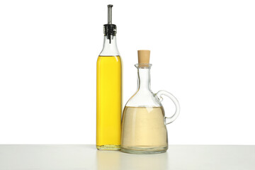 Oil and vinegar in bottles on table against white background
