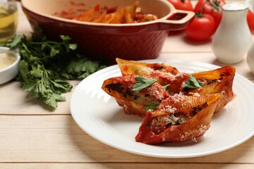 Delicious conchiglie pasta with ricotta cheese, tomato sauce and parsley on wooden table, closeup