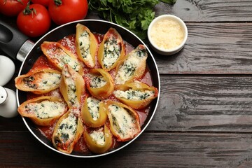 Delicious shell pasta stuffed with ricotta and spinach served on wooden table, flat lay. Space for text
