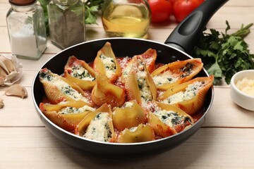 Delicious shell pasta stuffed with ricotta and spinach served on white wooden table, closeup