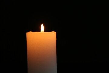 One burning candle on black background, closeup. Space for text
