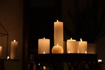 Many burning candles on wicker table indoors
