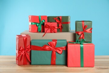 Parcel with gift boxes on wooden table against light blue background