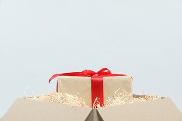Parcel with gift box on light background, closeup
