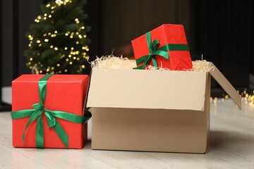 Parcel with gift boxes on floor in room decorated for Christmas. Bokeh effect
