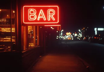 A neon sign for a bar is lit up in the night