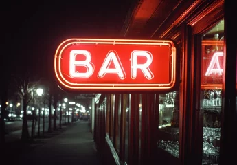 A neon sign for a bar is lit up in the night