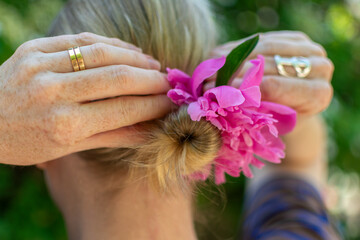 Blond woman fixing a flower in her bun.