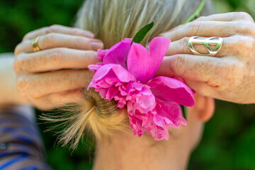 Blond woman fixing a flower in her bun.