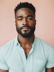 Poised African-American man with beard and green eyes in mint shirt against pastel coral background