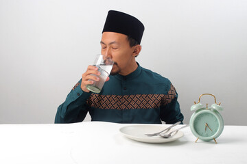 Asian Muslim man about to drink a glass of water to break his fast during Ramadan
