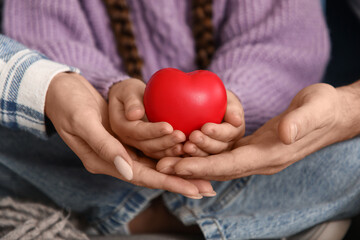 Happy couple with adopted girl holding heart at home, closeup