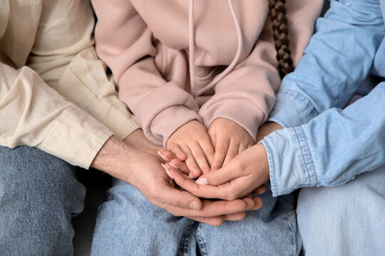 Couple with adopted girl holding hands, closeup