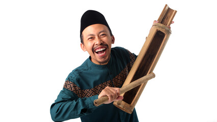 Excited Asian Muslim man holding a kentongan bamboo clapper to wake people up for Suhoor, the...