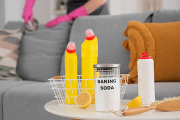 Baking soda with lemon on table against woman cleaning sofa in room, closeup