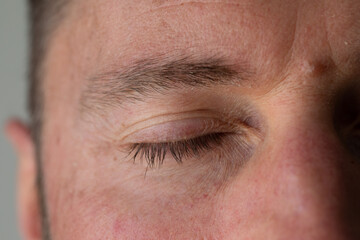 Obraz premium Man closing eyes showing wrinkles and eyelashes in close-up portrait