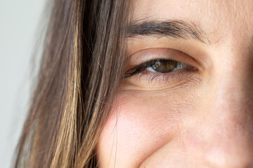 Close-up of woman's face showing green eye and hair: wellness and beauty concept