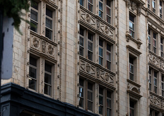 Fototapeta premium Historic and modern buildings in downtown Boston featuring intricate facades, brickwork, and Art Deco details. The urban architecture highlights the city's rich architectural heritage and design style